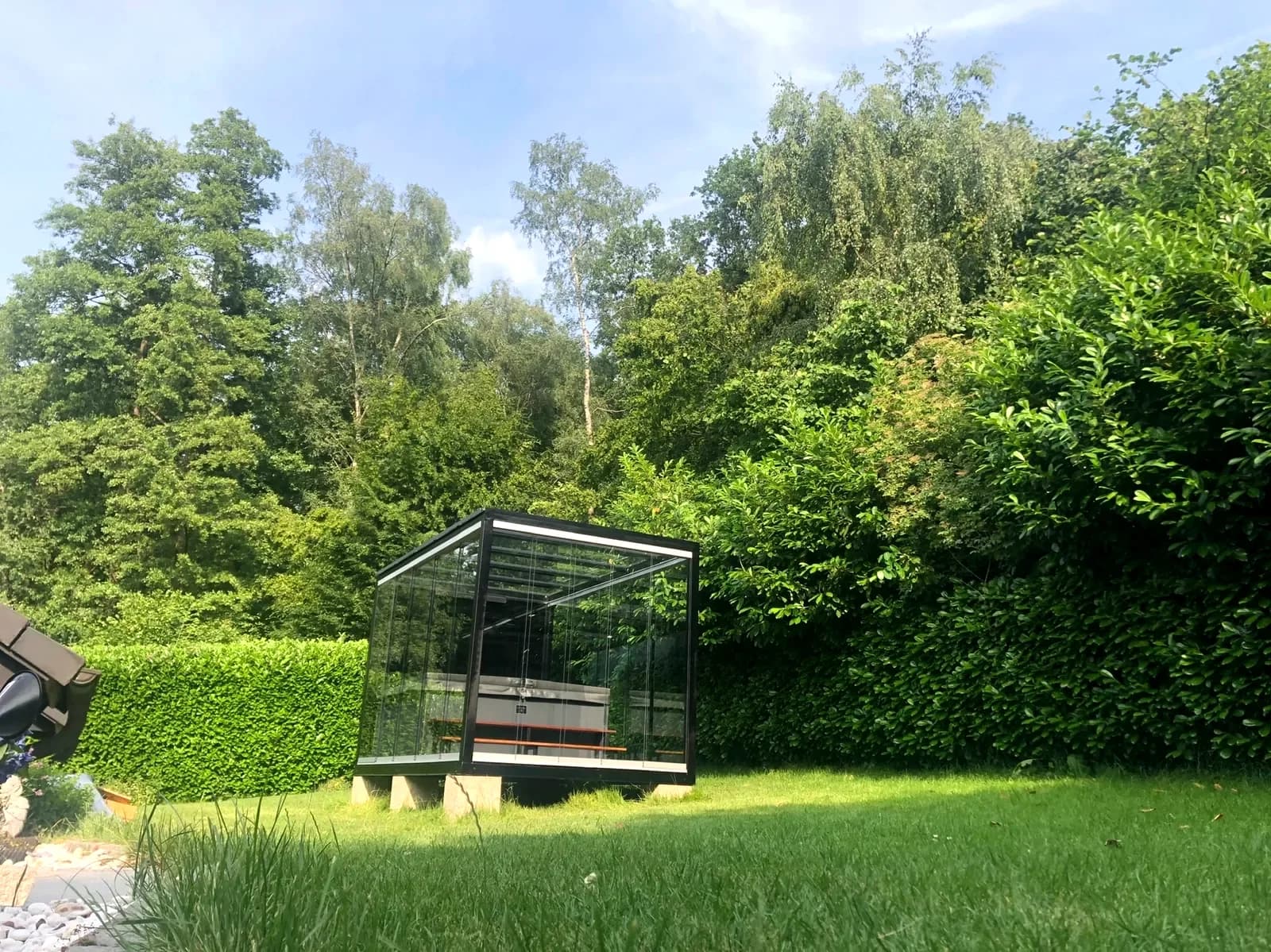 Kompakter REINHART Spa zwischen Hecken im Privatgarten auf Steinblöcken